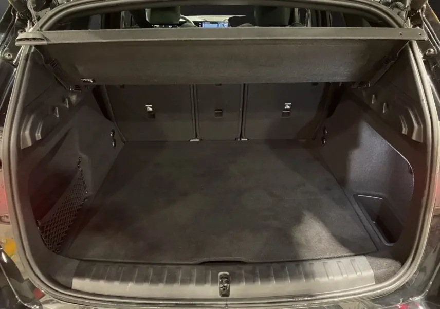 Coffre ouvert vu de l'arrière d'un BMW X1 noir 2025, montrant l'espace de chargement et la tablette de séparation.
