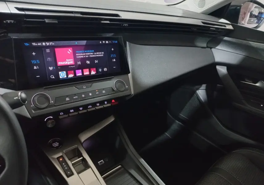 Vue intérieure côté passager de la Peugeot 308 PHEV 180 E-EAT8 Allure 2025, avec écran tactile central et console moderne.