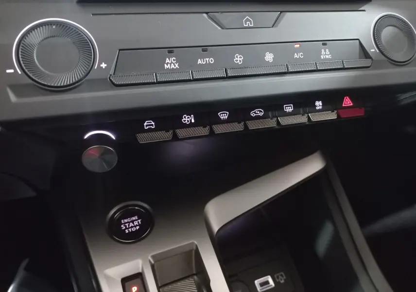 Détail de la console centrale de la Peugeot 308 PHEV 2025, avec commandes climatisation, bouton start/stop et ports USB.