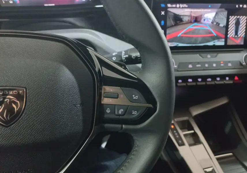 Vue intérieure rapprochée du volant cuir à commandes multifonctions côté droit et écran tactile affichant la caméra de recul.