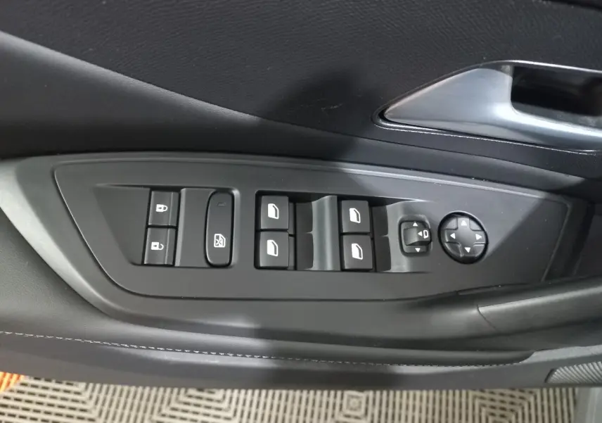 Gros plan sur la commande des vitres et rétroviseurs côté conducteur de la Peugeot 308 PHEV 180 Allure gris foncé.