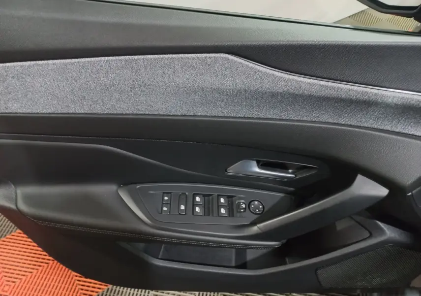 Gros plan sur la porte intérieure côté conducteur de la Peugeot 308 PHEV 180 Allure avec commandes de vitres et revêtement gris foncé.