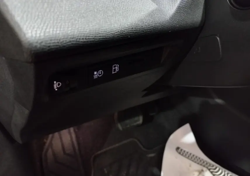 Détail intérieur côté conducteur de la Peugeot 308 PHEV 2025 montrant les commandes d’éclairage et de carburant sous le tableau de bord noir.