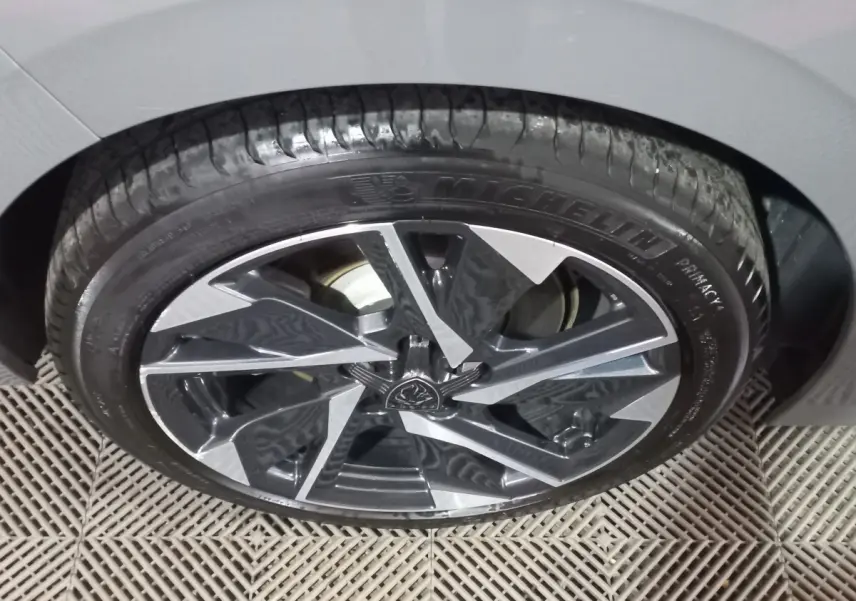 Gros plan sur la roue avant droite de la Peugeot 308 PHEV 180 E-EAT8 Allure gris foncé avec jante alliage stylisée.
