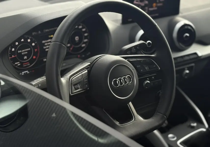 Vue rapprochée du volant cuir multifonction et du tableau de bord numérique de l'Audi Q2 30 TFSI S-Line 2024.