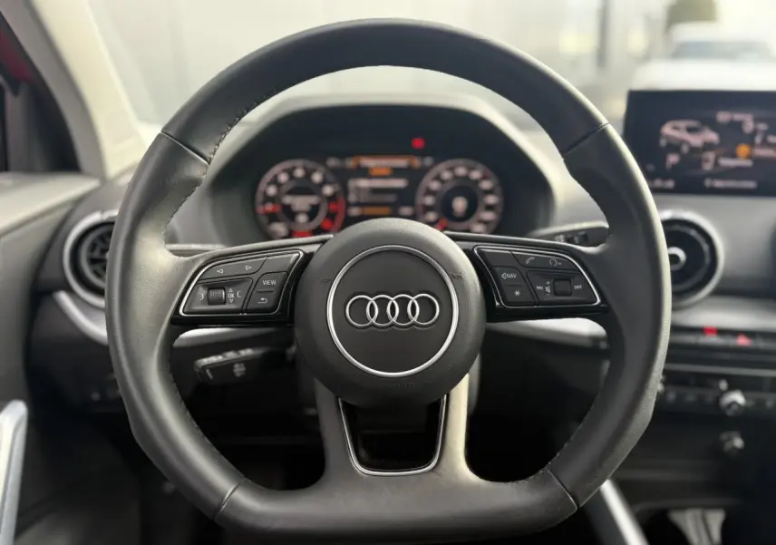 Volant cuir multifonction noir d'Audi Q2 30 TFSI S-Line 2024 avec tableau de bord numérique en arrière-plan.