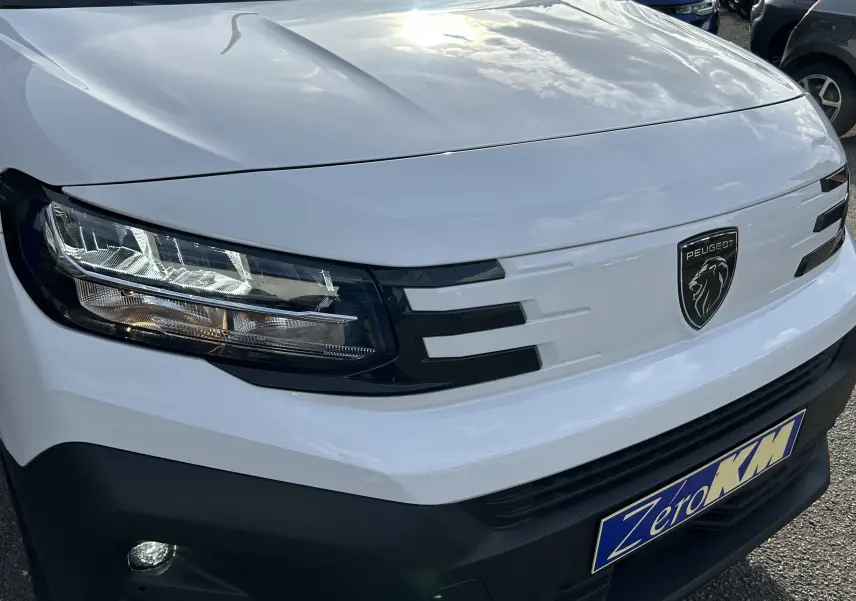 Gros plan sur l'avant blanc du Peugeot Partner Fourgon 2025 avec calandre noire et phares LED modernes.