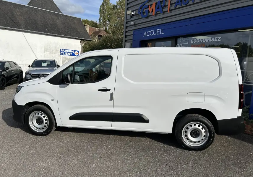 Profil droit d'un utilitaire blanc Peugeot Partner Fourgon 2025 avec plancher bois visible sur le côté et jantes acier.