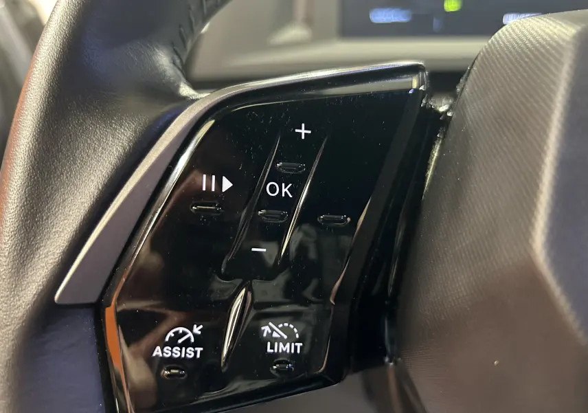 Gros plan sur les commandes noires du volant du Peugeot 5008 gris Artense, avec boutons Assist et Limit visibles.