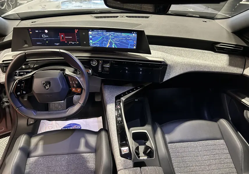 Vue intérieure avant du Peugeot 5008 hybride 2025, tableau de bord moderne avec écran numérique et sellerie gris Artense.