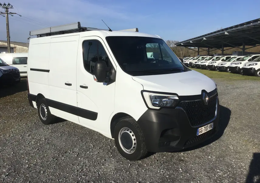 Vue 3/4 avant droite d’un Renault Master blanc avec galerie de toit et pare-chocs noirs sur un parking.