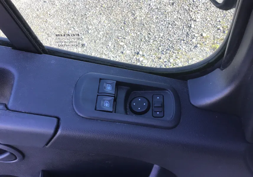 Gros plan sur les commandes électriques des vitres et rétroviseurs côté gauche du Renault Master blanc 2022.