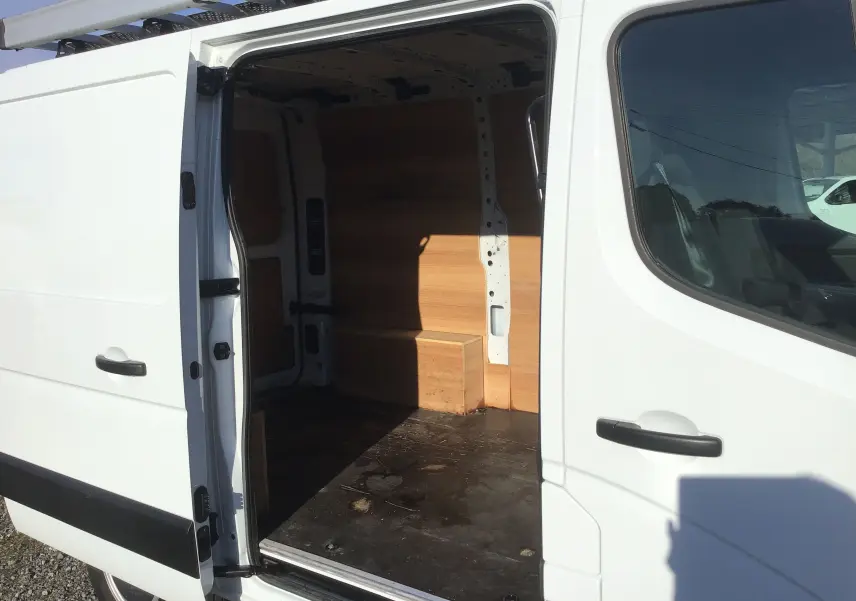 Renault Master blanc vu de côté gauche avec porte coulissante ouverte montrant l'intérieur boisé du fourgon.
