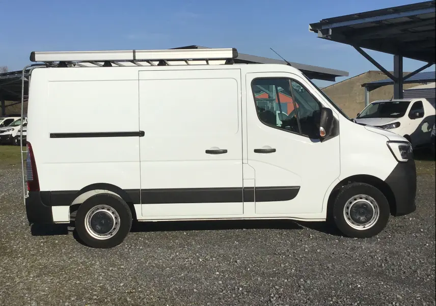 Vue de profil côté gauche d’un Renault Master blanc 2022 avec galerie de toit et porte latérale coulissante.