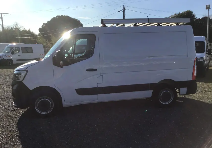 Vue latérale gauche d’un Renault Master blanc 2022 avec galerie de toit et bande noire sur le bas de caisse.