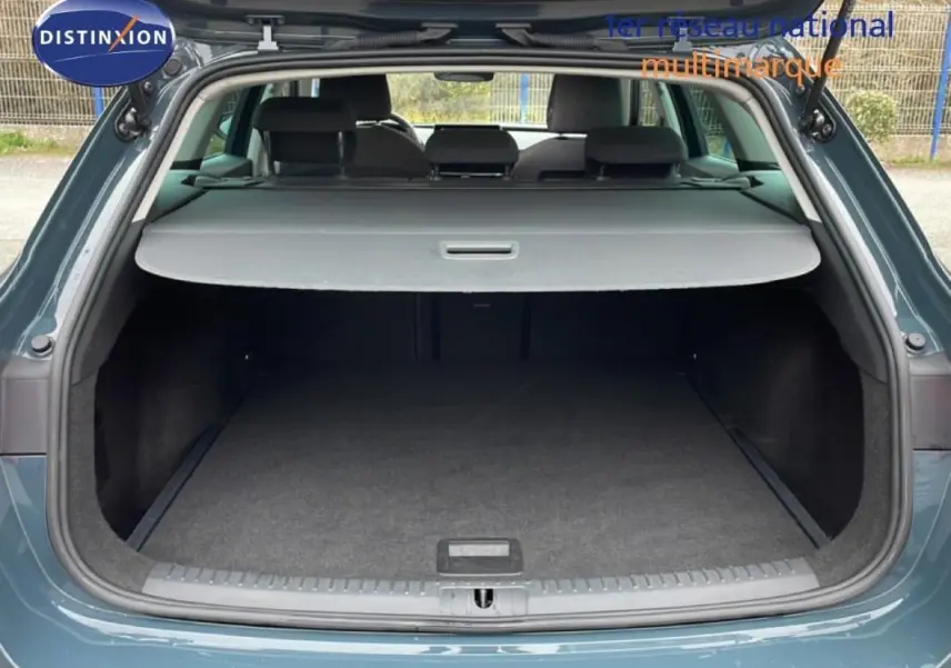 Coffre ouvert vu de l'arrière d'une SEAT Leon ST IV bleu avec cache bagages et intérieur spacieux.