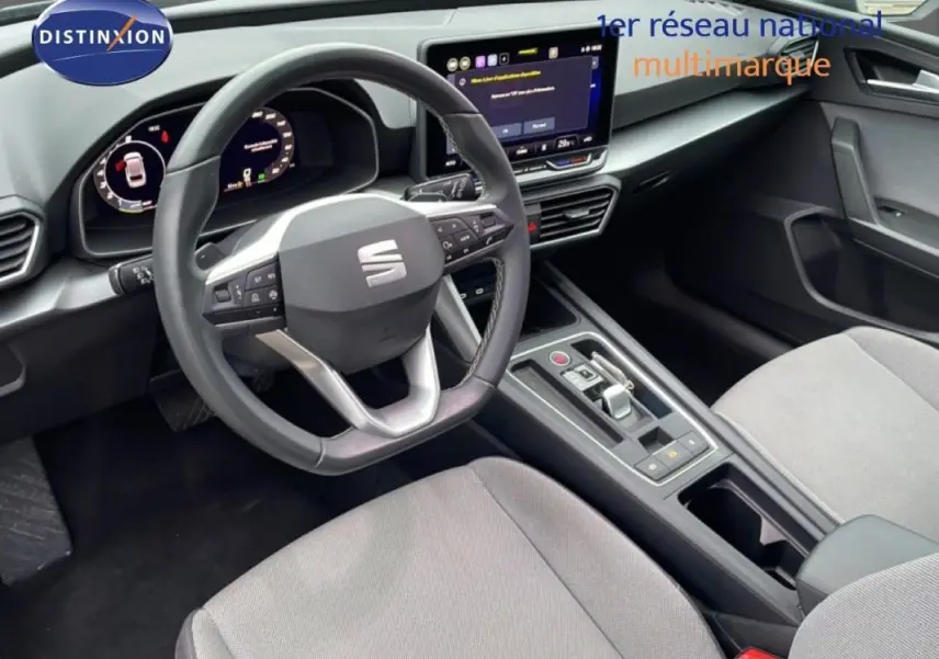 Vue intérieure côté conducteur du SEAT Leon ST IV 2025, volant cuir multifonctions et écran tactile central visible.