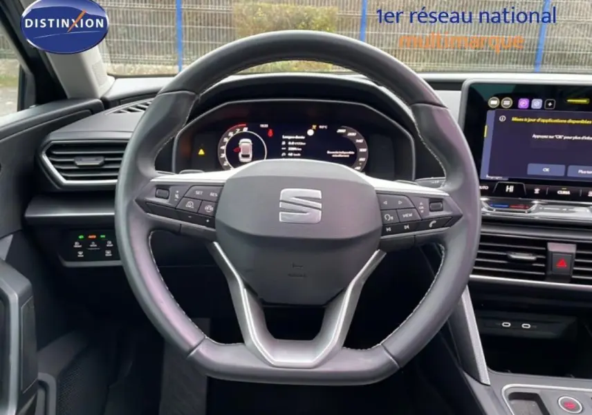 Vue intérieure centrée sur le volant cuir multifonctions d’une SEAT Leon ST IV 2025 avec écran tactile et tableau de bord numérique.