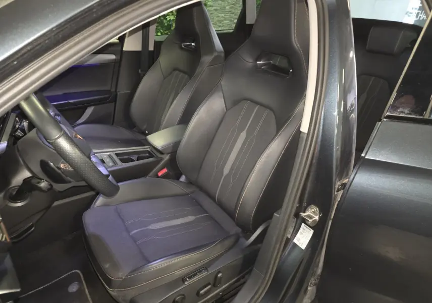Vue intérieure côté conducteur du CUPRA Leon Sportstourer gris, mettant en valeur les sièges baquets noirs avec surpiqûres copper.
