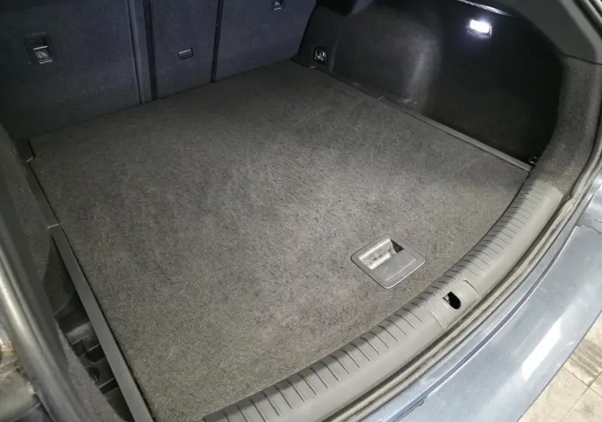 Coffre ouvert vu de dessus du CUPRA Leon Sportstourer gris avec tapis de sol et éclairage intérieur.