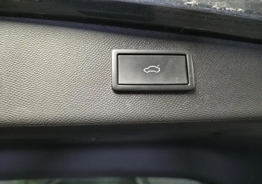 Bouton noir d'ouverture électrique du hayon sur la garniture intérieure d'un CUPRA Leon Sportstourer gris 2024.