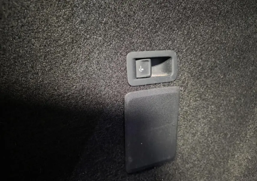 Détail du bouton de rabattement des sièges arrière dans le coffre du CUPRA Leon Sportstourer gris 2024.