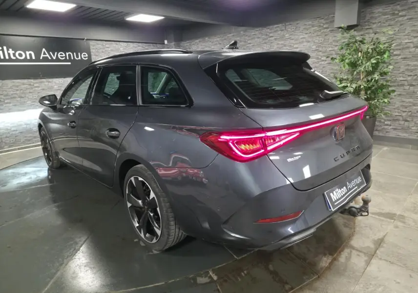 Vue 3/4 arrière droite d'une CUPRA Leon Sportstourer gris magnétique avec feux arrière LED et crochet d'attelage visible.