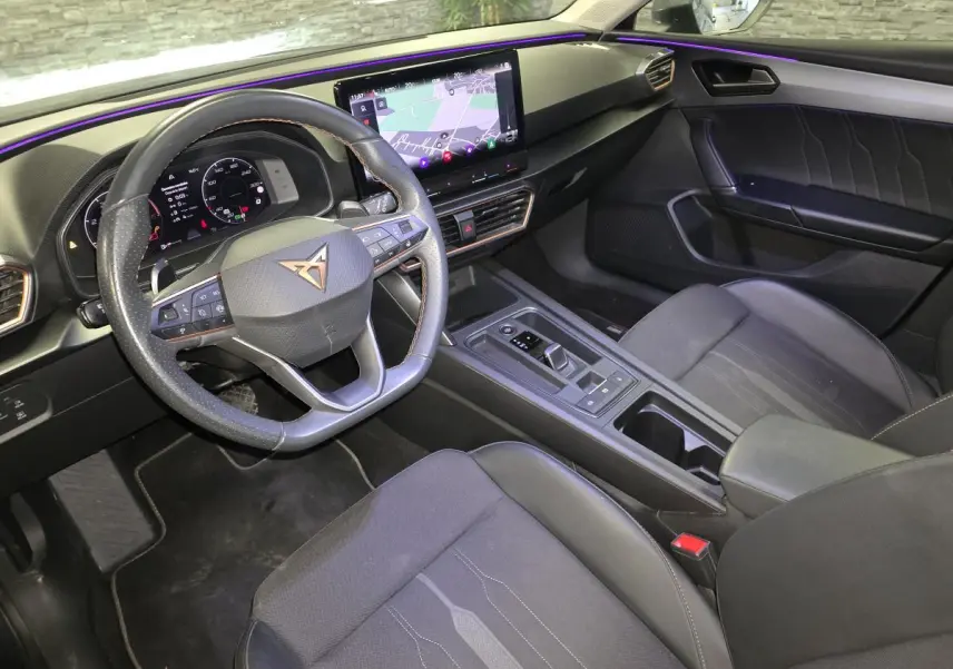 Vue intérieure côté conducteur de la CUPRA Leon Sportstourer 2024 avec tableau de bord digital et volant cuir noir surpiqué copper.