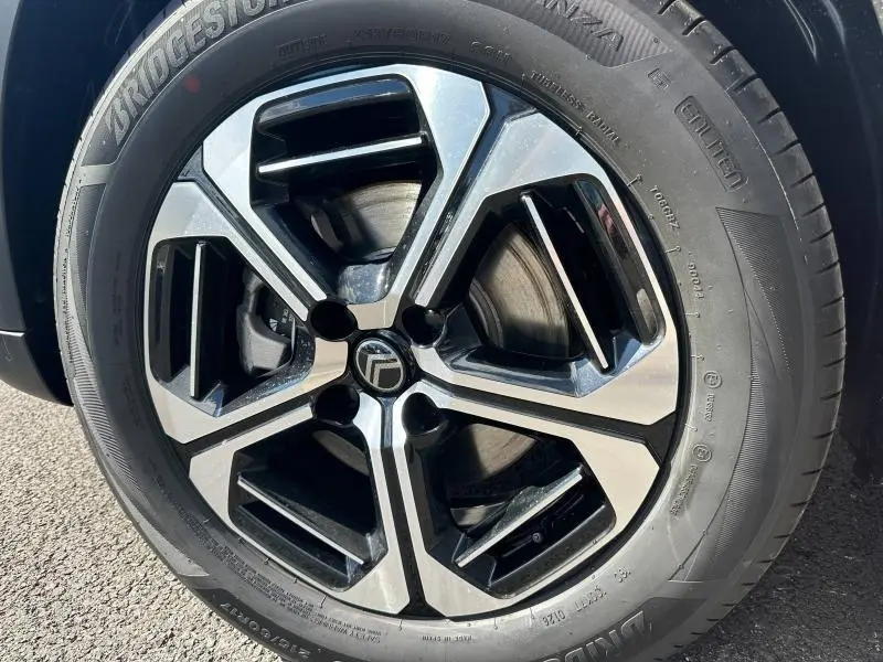 Gros plan sur la jante alliage bicolore noire et argentée du Citroën C3 Aircross Gris Mercury, avec pneu Bridgestone visible.