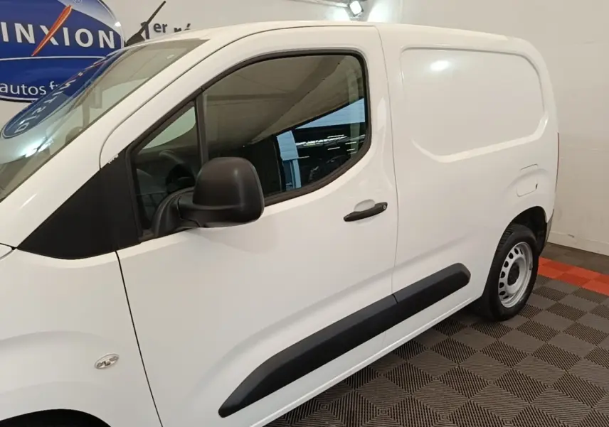 Vue de profil côté gauche d’un utilitaire Citroën Berlingo blanc avec protections latérales noires dans un garage.