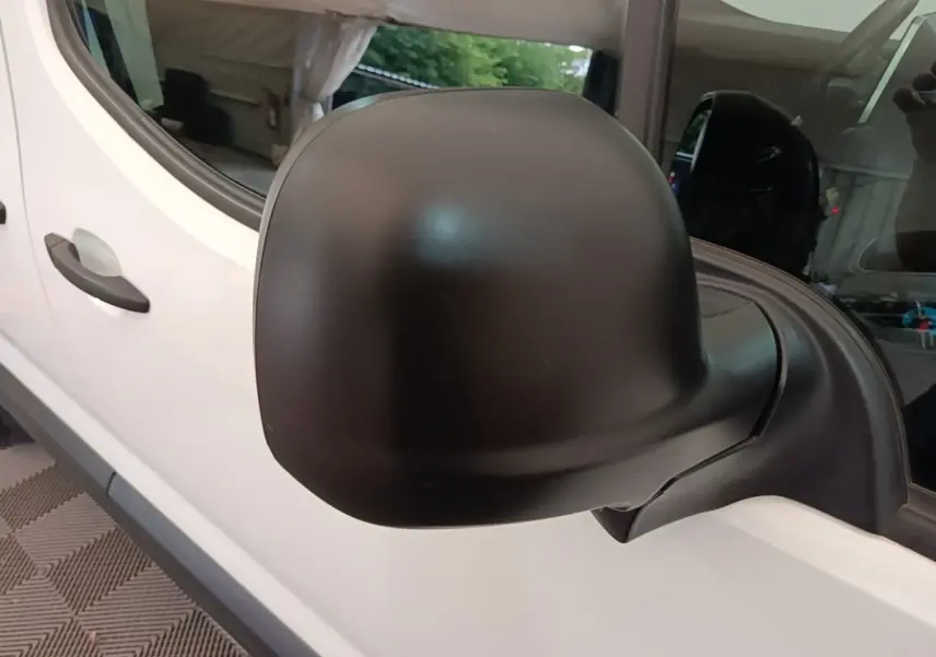 Gros plan sur le rétroviseur noir côté droit d’un Citroën Berlingo blanc, vue latérale avant.
