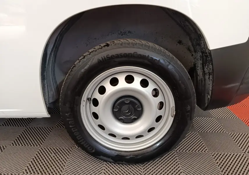 Gros plan sur la roue arrière droite d’un Citroën Berlingo blanc, jante acier avec pneu Continental AllSeasonContact.