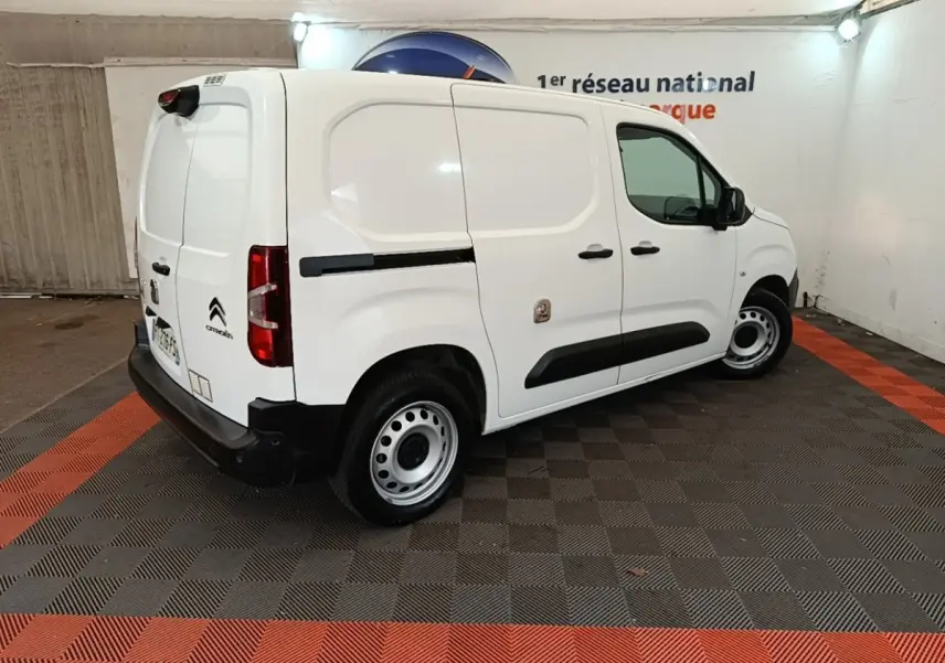 Vue 3/4 arrière droite d’un utilitaire Citroën Berlingo blanc avec protections latérales noires et jantes acier.