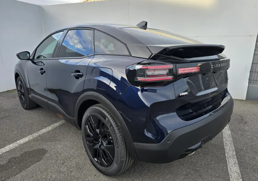 Vue 3/4 arrière droite d'une Citroën C4 III hybride bleu éclipse avec toit noir et jantes noires brillantes