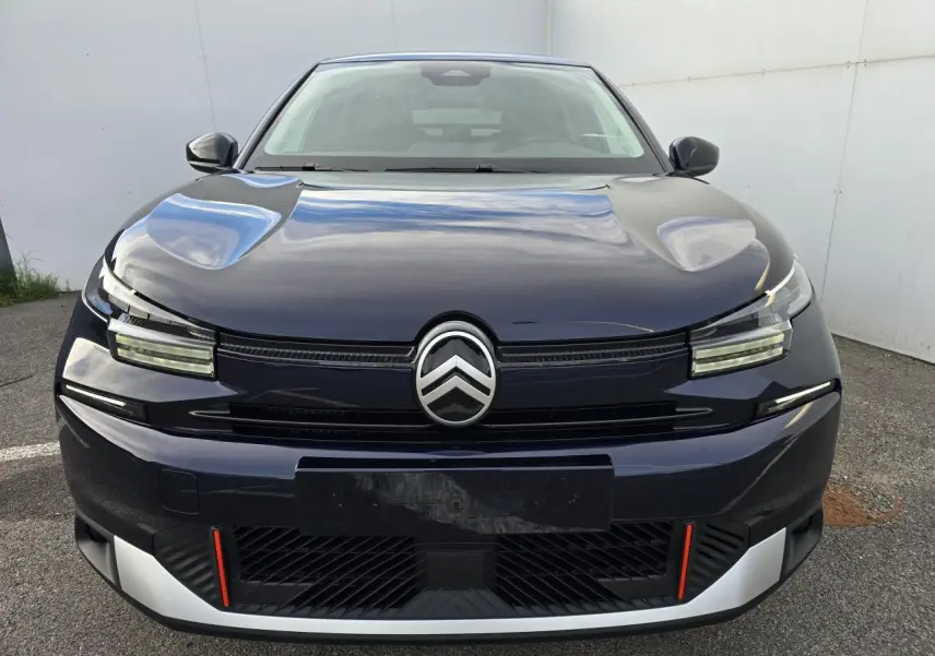 Vue frontale d'une Citroën C4 III hybride 2025 bleu eclipse avec toit noir et détails rouges sur le pare-chocs.