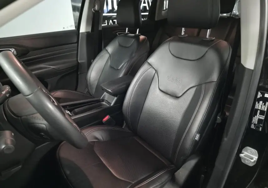 Vue intérieure côté conducteur du Jeep Compass 2022 avec sièges en cuir noir embossés du logo Jeep.