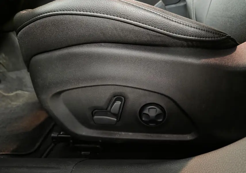 Réglage électrique du siège conducteur en cuir noir dans le Jeep Compass 2022, vue latérale rapprochée.