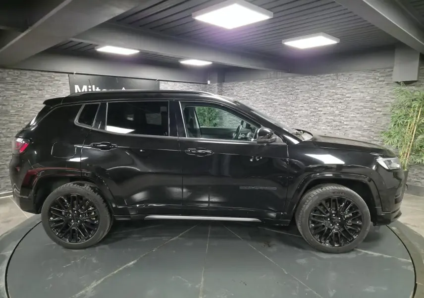 Jeep Compass 2022 noir vue profil côté gauche, avec jantes alliage noires et toit noir en intérieur showroom.