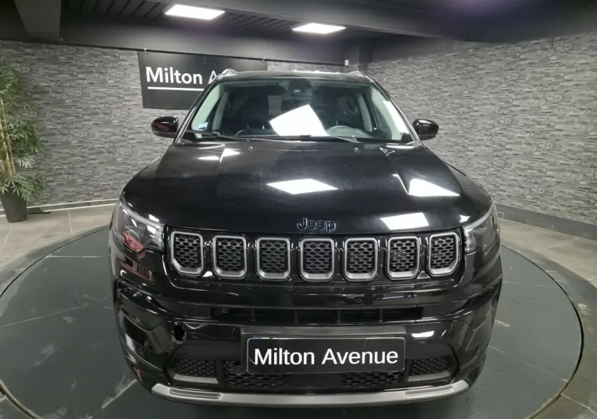 Vue frontale d'un Jeep Compass noir brillant avec calandre à sept fentes et plaque Milton Avenue.