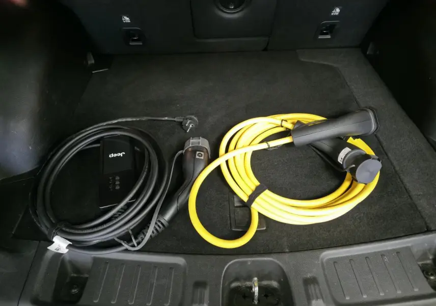 Vue du coffre noir du Jeep Compass 2022 avec câbles de recharge type 2 noir et jaune pour hybride rechargeable.