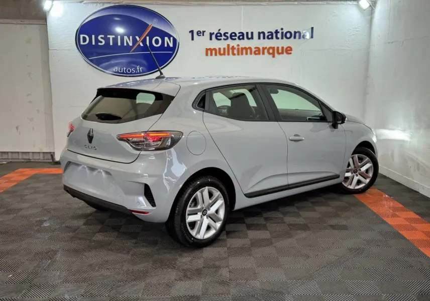 Renault Clio Evolution Blue dCi 100 gris clair vue 3/4 arrière droit en intérieur avec feux arrière allumés.