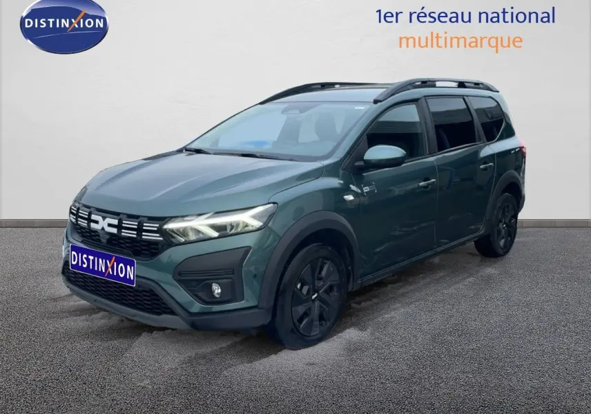 Vue 3/4 avant droite d'un Dacia Jogger vert cèdre métallisé avec jantes noires et barres de toit.