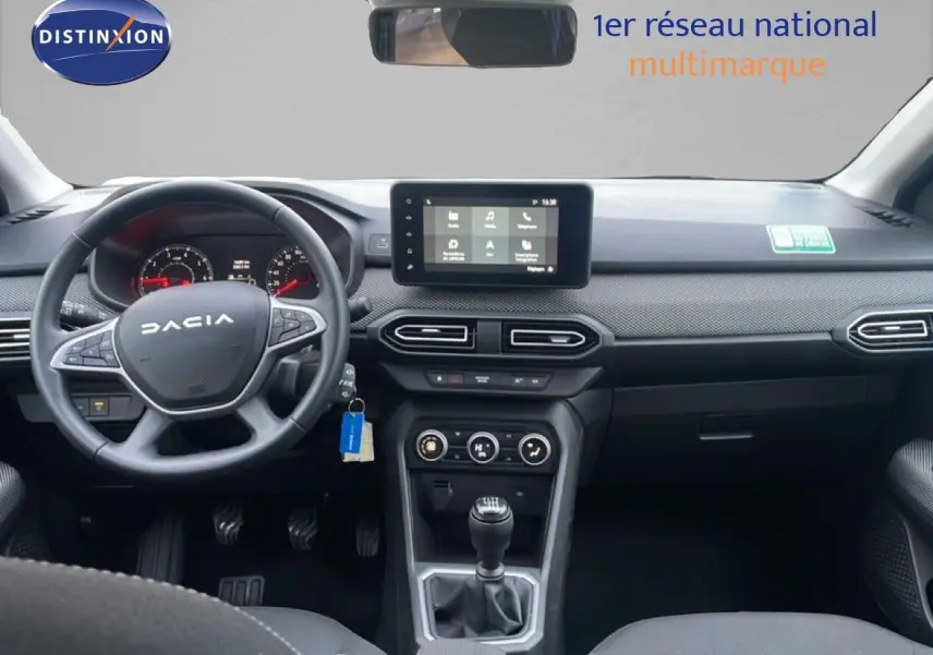 Vue intérieure avant du tableau de bord et volant noir du Dacia Jogger 2025, avec écran tactile central et levier de vitesses manuel.