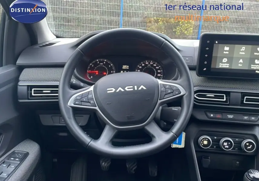 Vue intérieure centrée sur le volant DACIA d'un Jogger 2025 avec tableau de bord et écran tactile visibles.