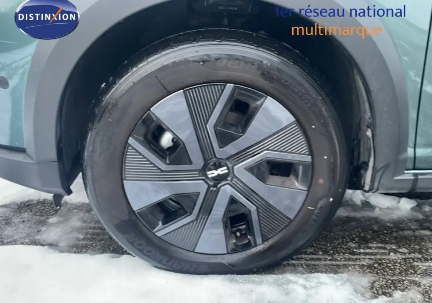 Gros plan sur la roue avant droite du Dacia Jogger vert cèdre métal avec jante noire au design géométrique.