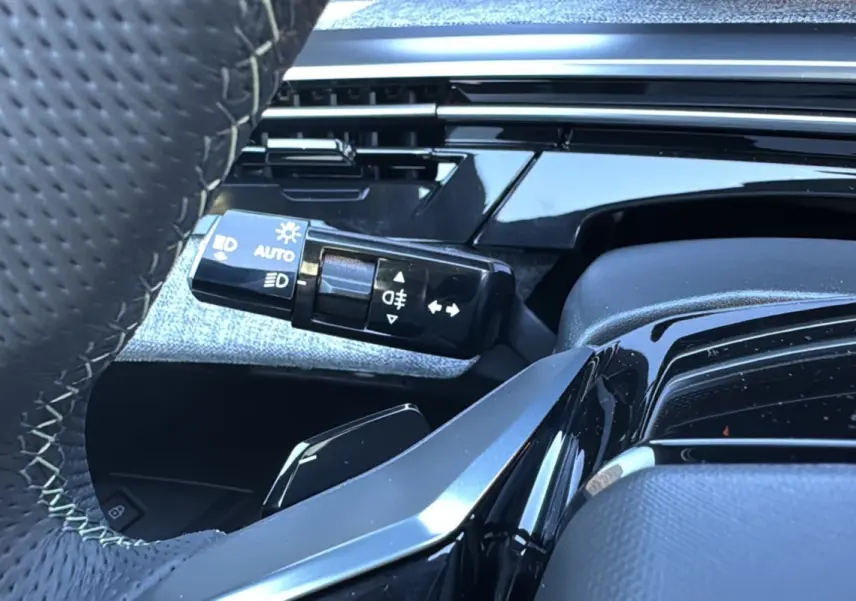 Gros plan sur la commande des phares et clignotants à gauche du volant cuir du Peugeot 3008 blanc okénite.