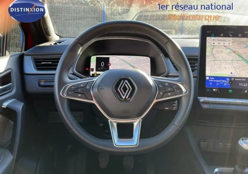 Vue centrée sur le volant cuir d'une Renault Captur rouge 2025 avec cockpit numérique et écran tactile GPS.