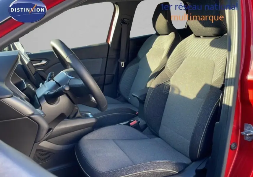 Vue intérieure côté conducteur du Renault Captur rouge 2025, montrant sièges tissu gris et volant multifonctions cuir.