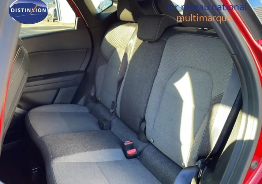 Vue intérieure sur les sièges arrière gris du Renault Captur rouge, avec ceinture de sécurité et ouverture de porte visible.