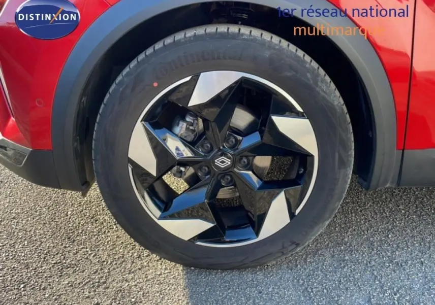 Gros plan sur la roue avant droite avec jante aluminium bicolore du Renault Captur rouge 2025.